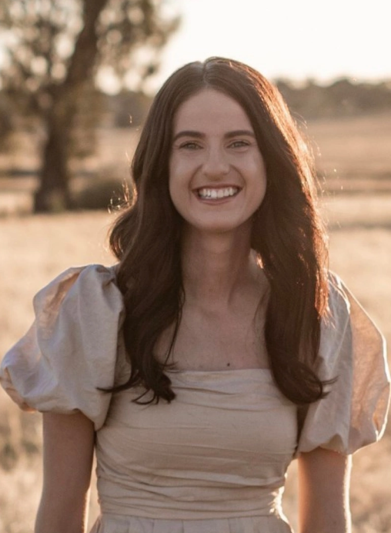 Woman smiling in cream dress outdoors. Professional web design and digital services company specializing in custom website creation.